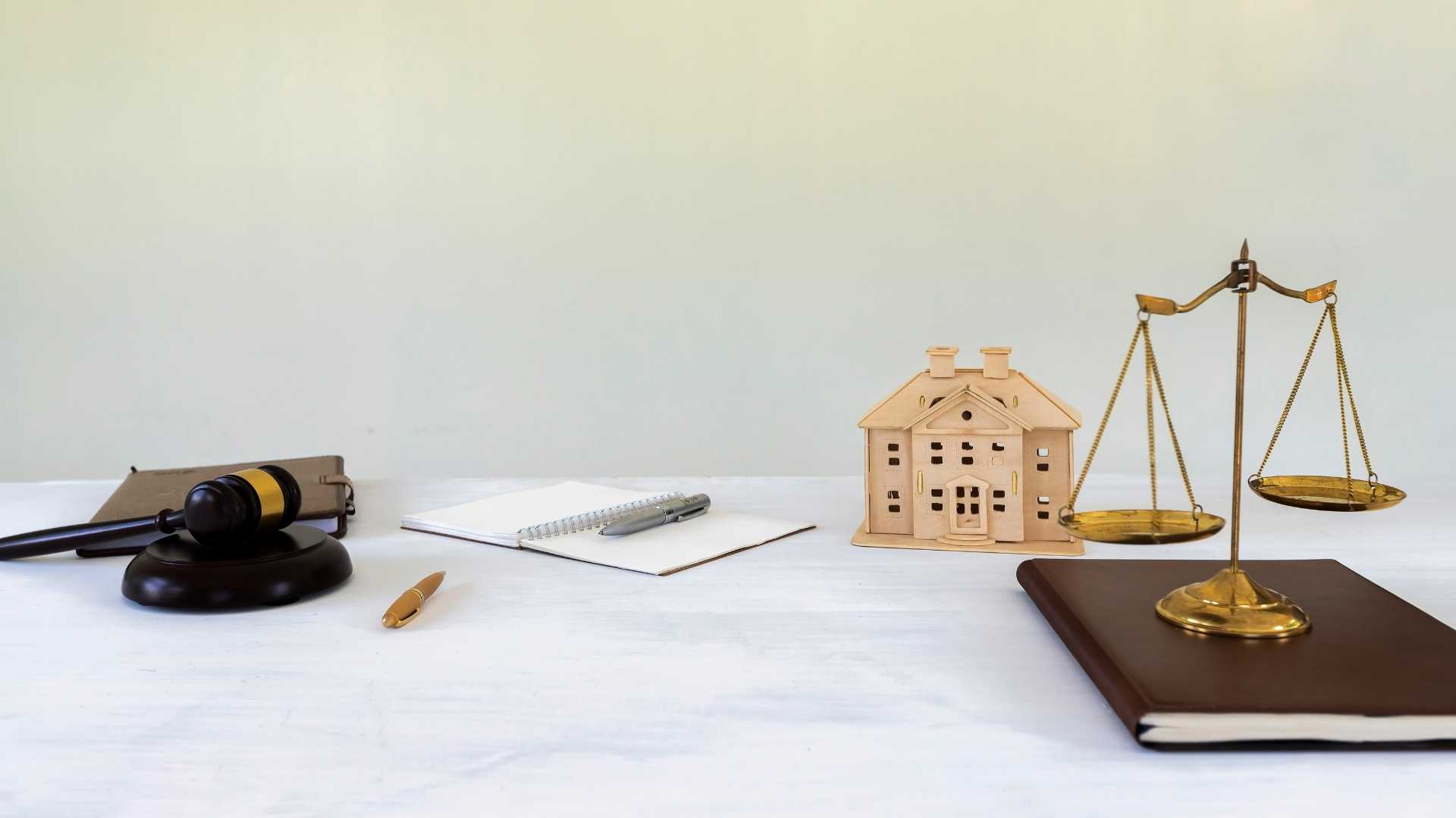 gavel, balance and house figurine on a table to symbolize housing laws